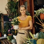 Happy owner of garden center potted flower and looking at camera.